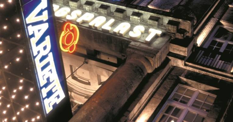 Beleuchtete Fassade des GOP Varieté-Theaters bei Nacht mit leuchtenden Schriftzügen und Neonlichtern an einem historischen Gebäude.